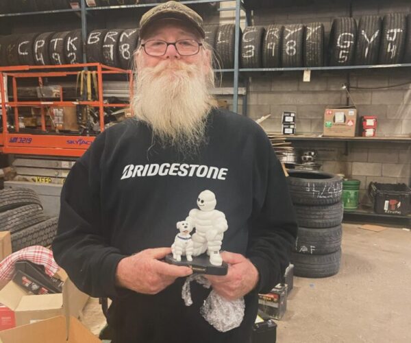 Niagara Battery & Tire employee holding Michelin tire mascot statue. 